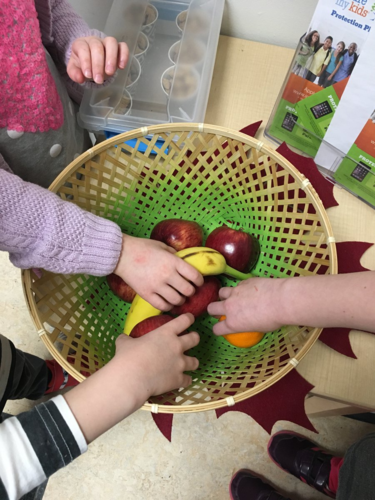 picture of students with hands in a basket full of fruit